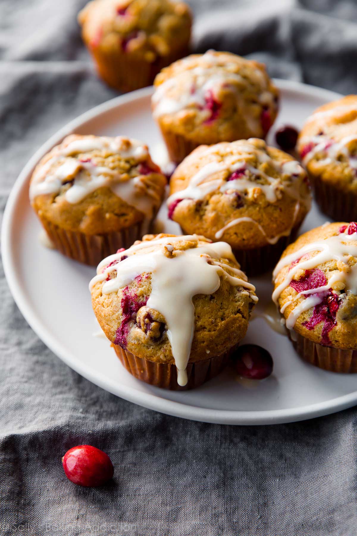 cranberry cardamom spice muffins with orange icing on a white plate