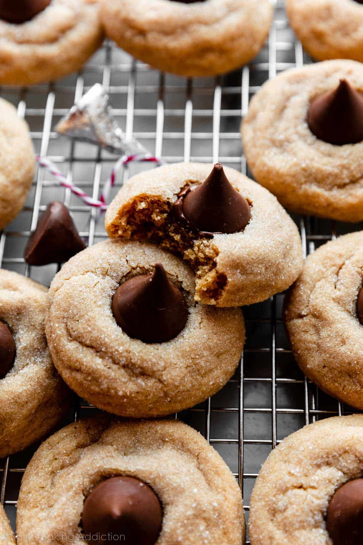 Hershey's Kiss peanut butter blossoms cookies on cooling rack with 1 bite taken out of a cookie.