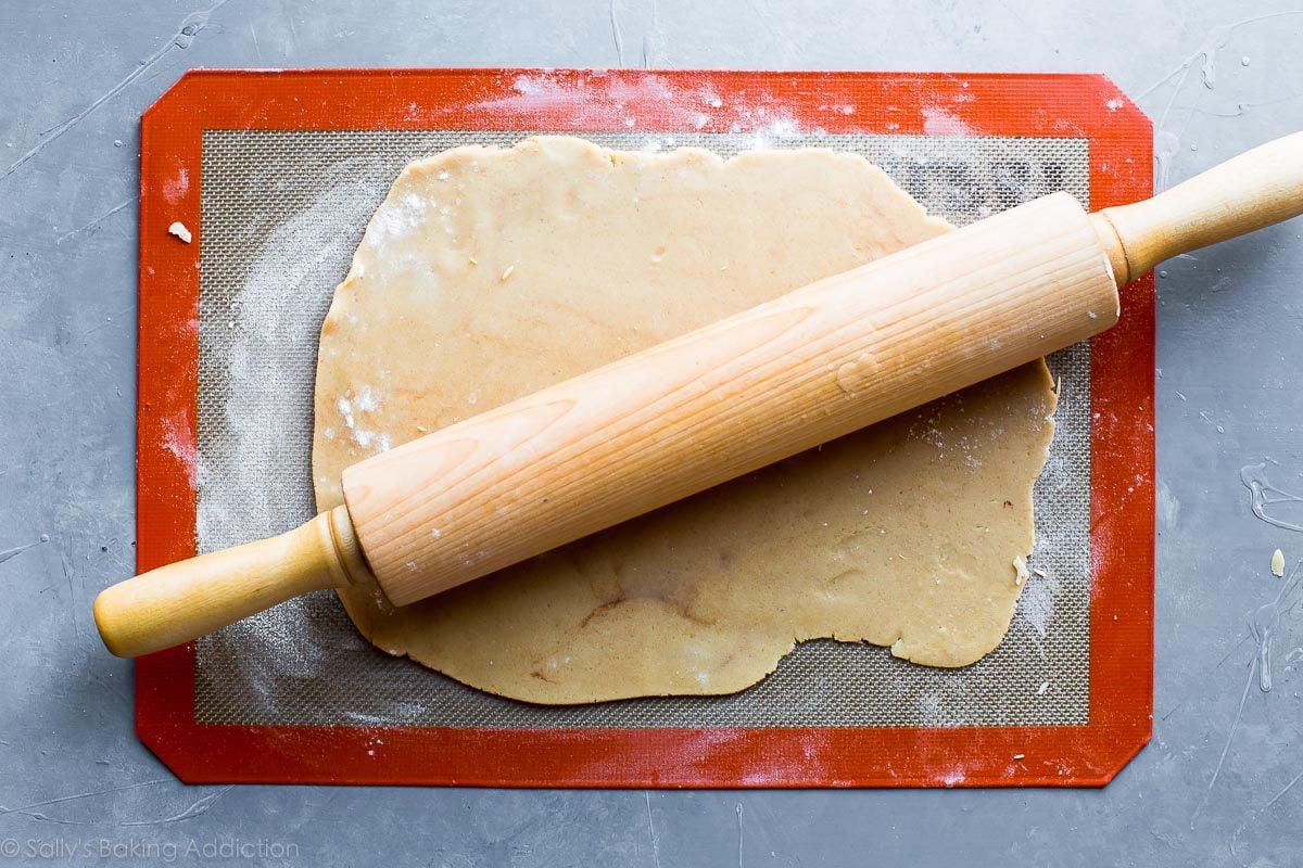 maple sugar cookie dough rolled out on a silpat baking mat with a wood rolling pin