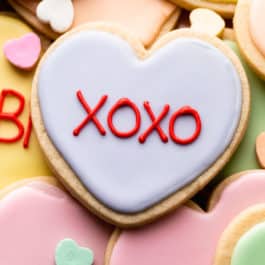 close-up of heart-shaped Valentine's Day cookie decorated with pastel purple royal icing with xoxo piped on top.