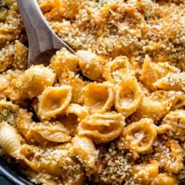 baked macaroni and cheese in a cast iron skillet with a wood spoon