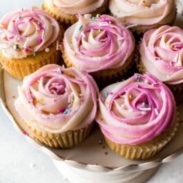 cupcakes with pink frosting roses on top on a cake stand