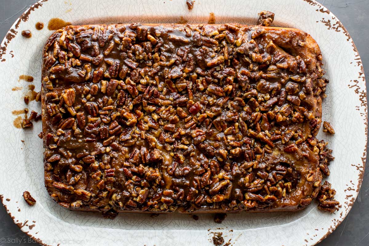 overhead image of maple pecan sticky buns with pecan topping on a white serving tray