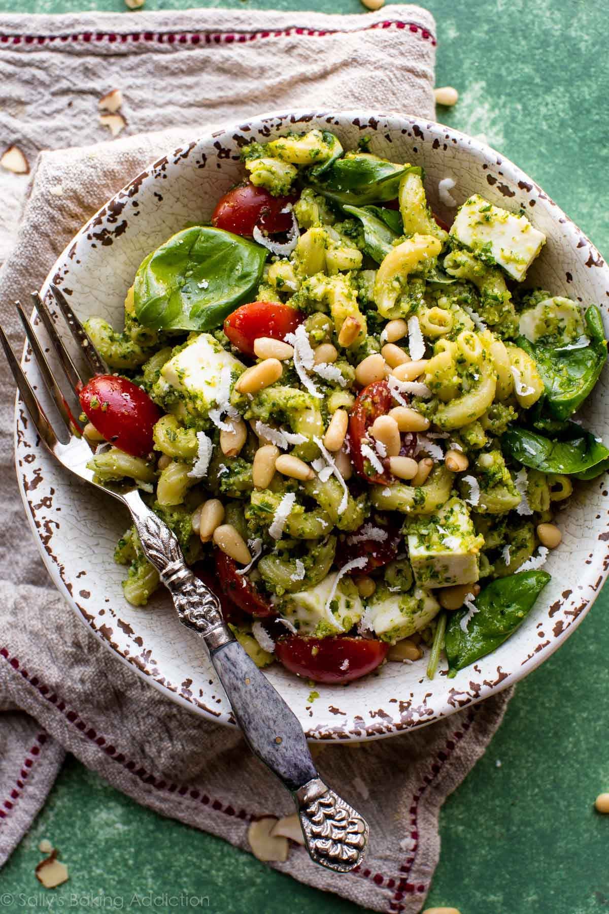 pesto pasta salad in a ceramic bowl with a fork