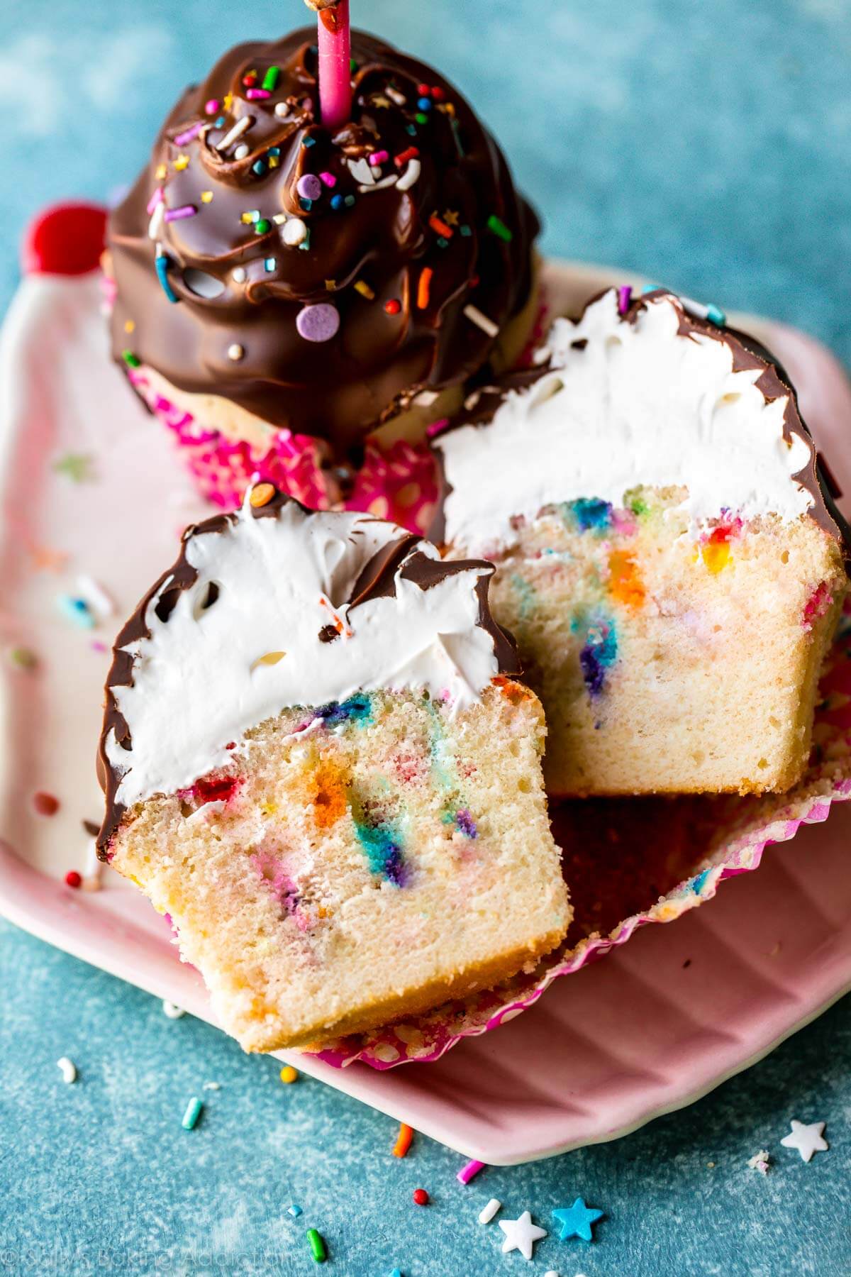 ultimate birthday cupcakes on a cupcake shaped plate with one cupcake cut in half showing meringue frosting under chocolate coating