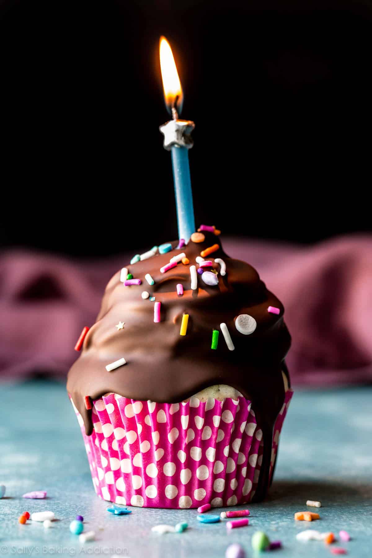 birthday cupcake with chocolate coating and a lit candle