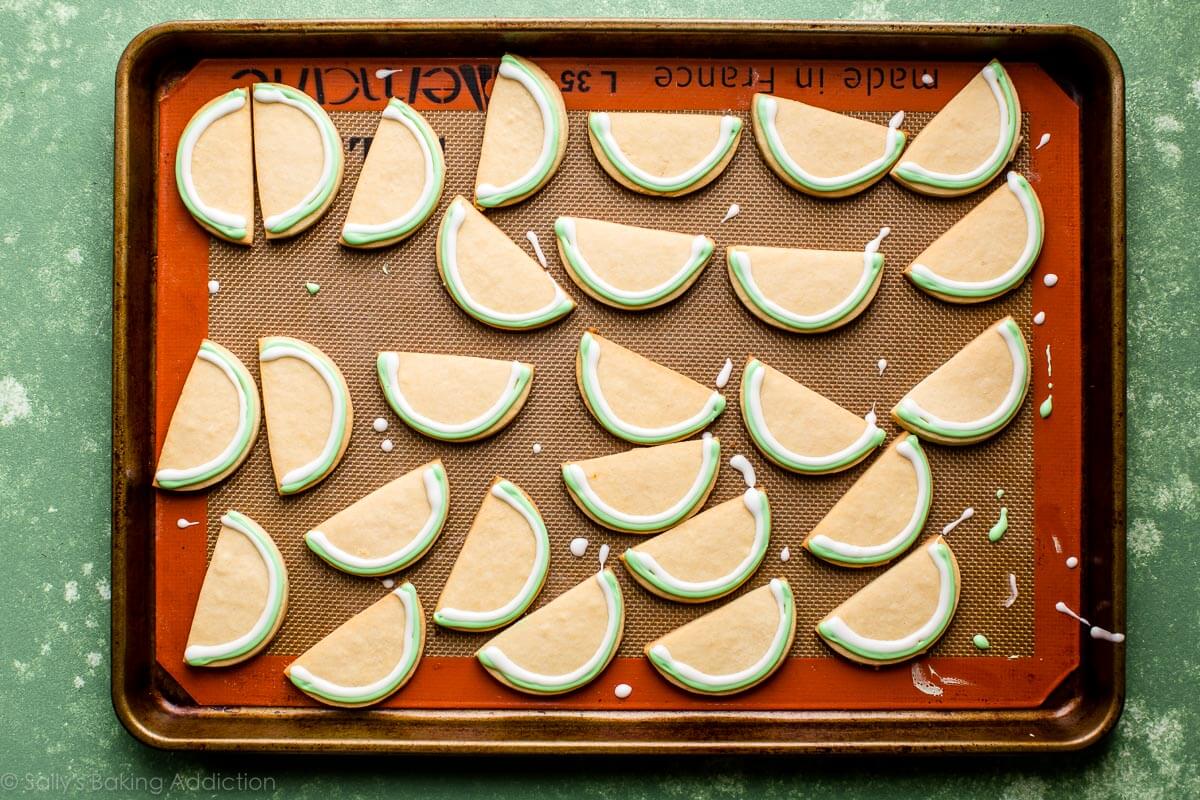 sugar cookies on a baking sheet with green and white royal icing decorated rinds