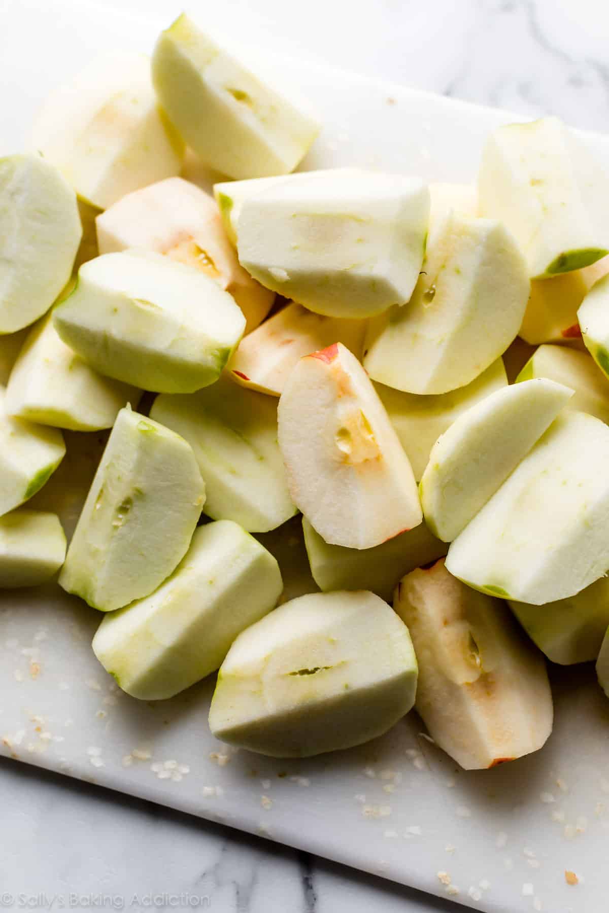 peeled and cut apples on white cutting board.