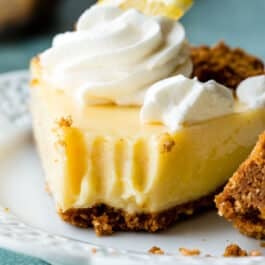 slice of lemon pie topped with whipped cream on a white plate