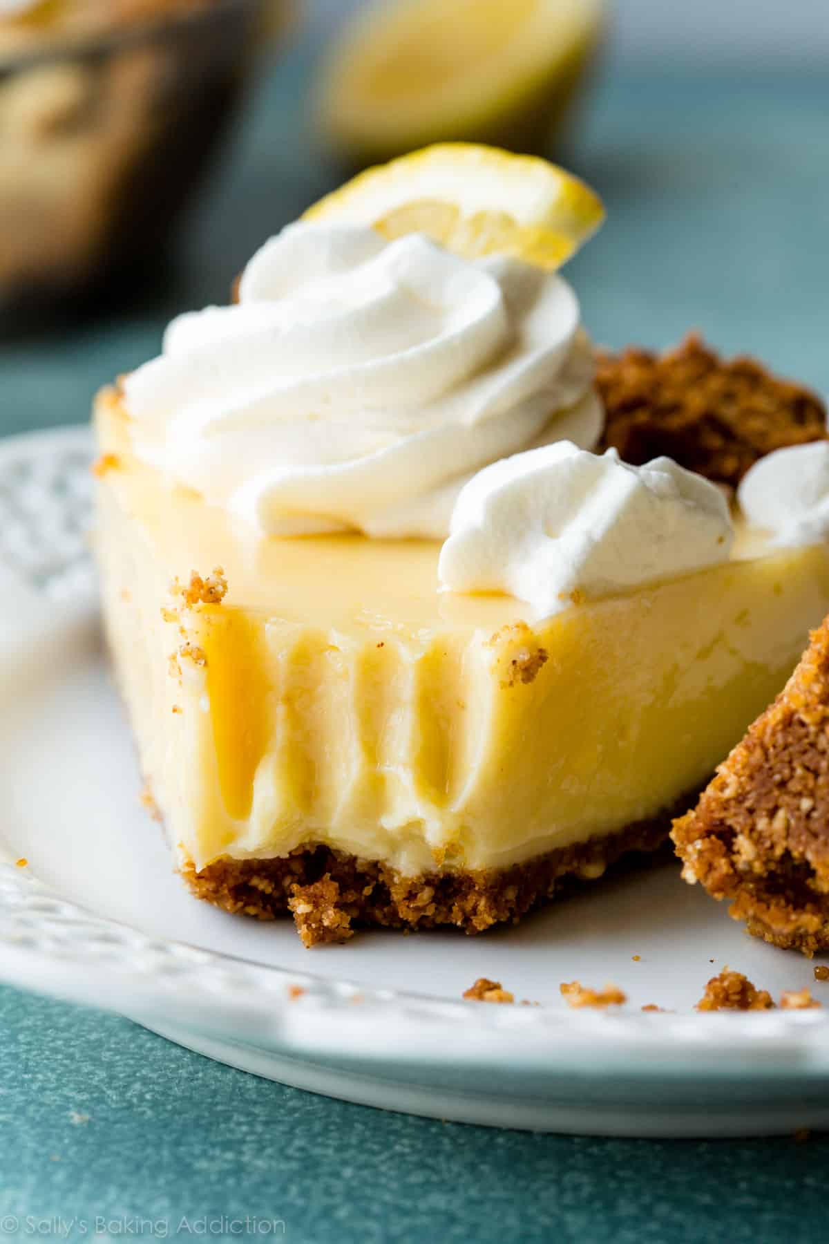 slice of lemon pie topped with whipped cream on a white plate