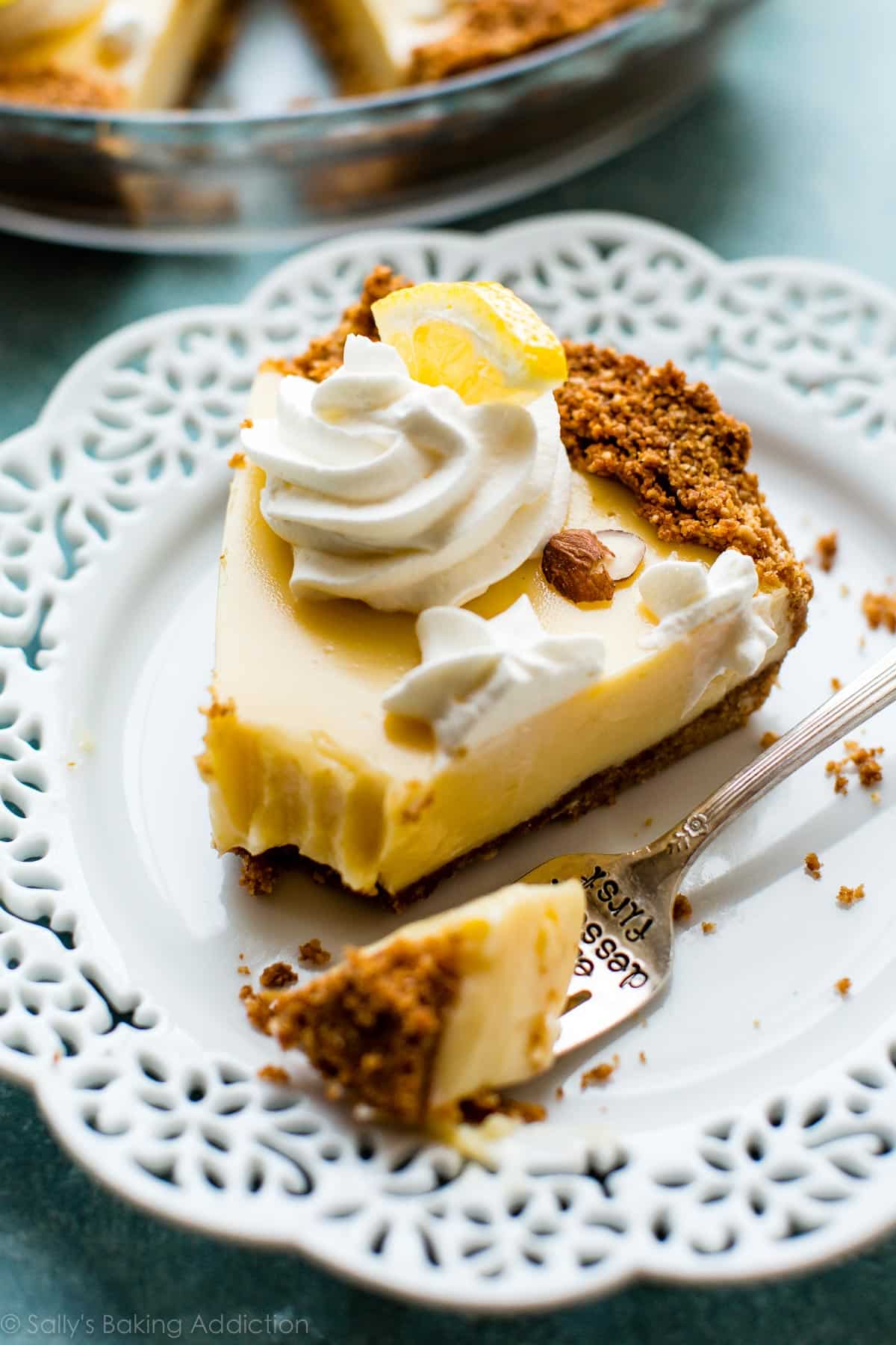 slice of lemon pie topped with whipped cream on a white plate with a fork