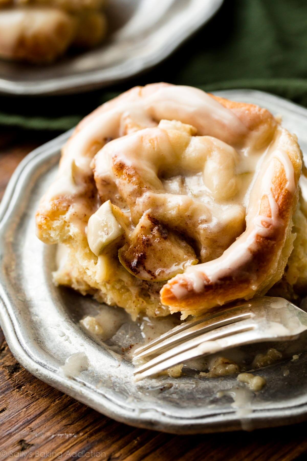 apple cinnamon roll on a silver plate with a fork