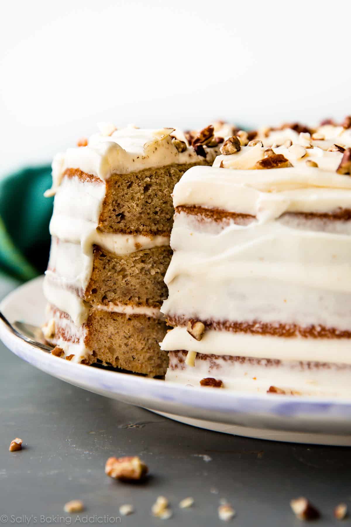 banana layer cake on a plate with a slice of cake on a dessert serving utensil being removed showing the layers