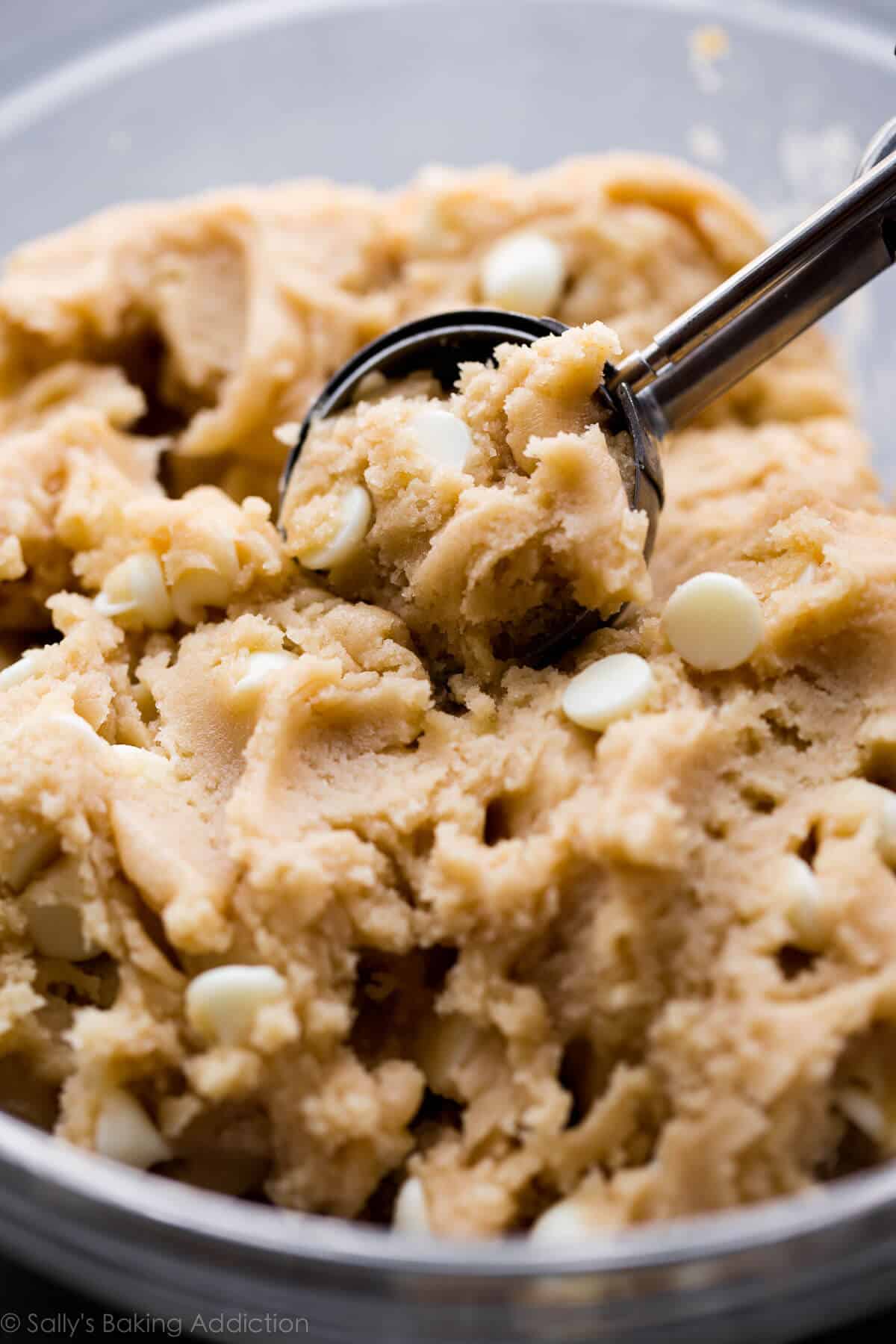 white chocolate chai snickerdoodle cookie dough in a glass bowl with a cookie scoop