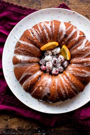 overhead image of cranberry orange bundt cake with sugared cranberries and orange slices in the middle