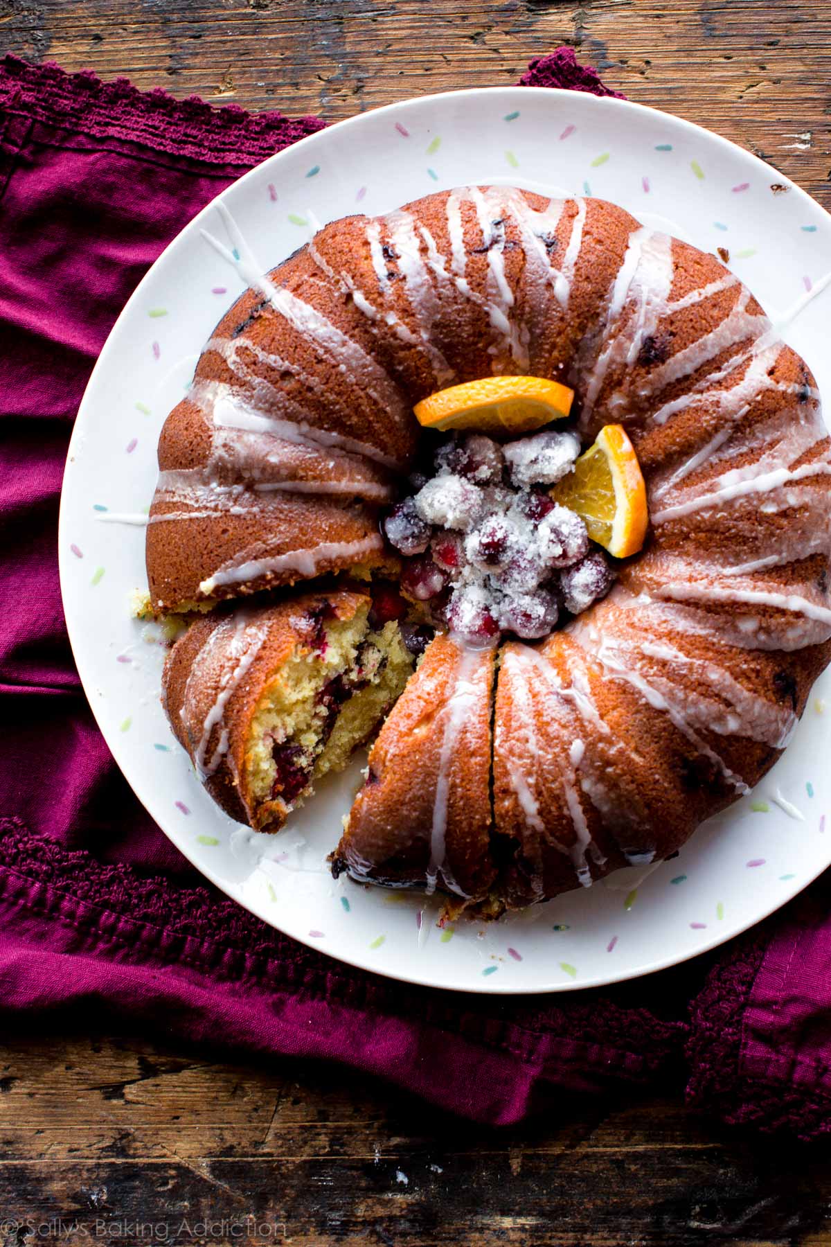 overhead image of cranberry orange bundt cake with sugared cranberries and orange slices in the middle