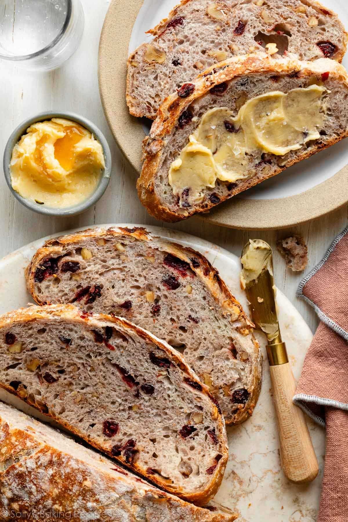 cranberry nut bread slices with butter on plate and marble tray.