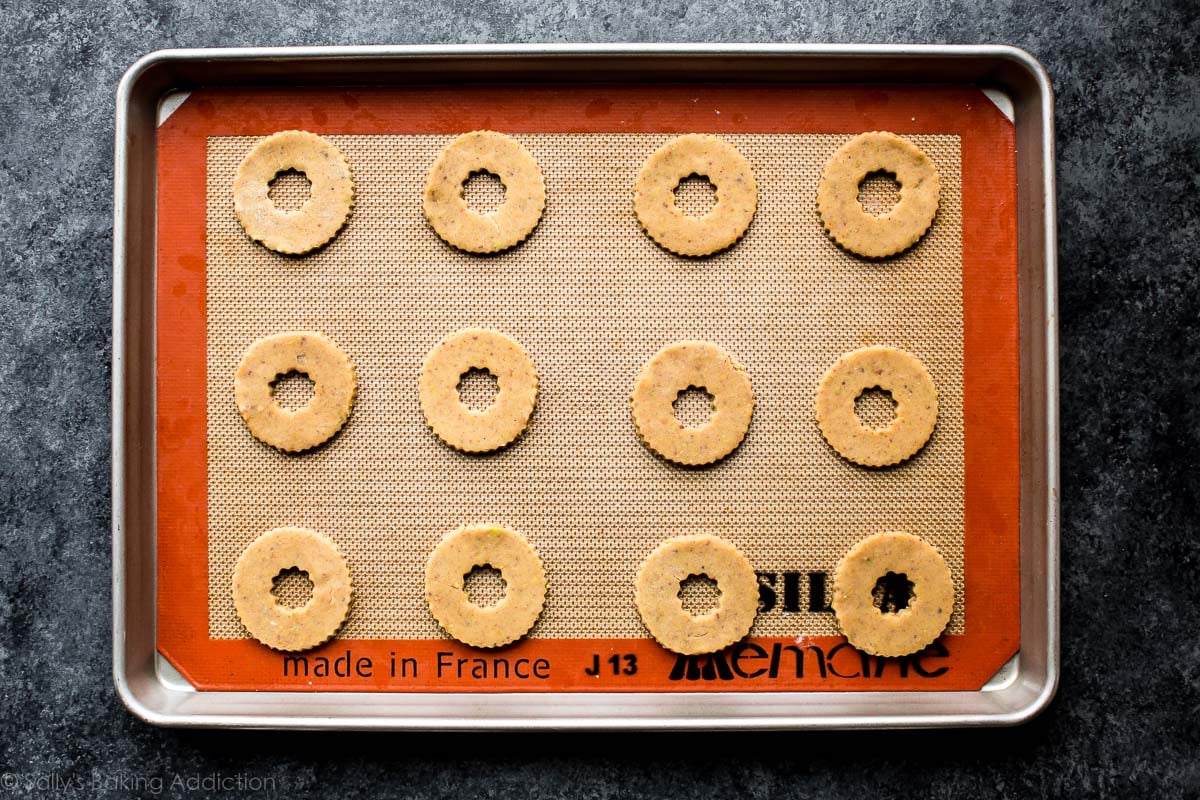 linzer cookie dough with centers cut out on a baking sheet before baking