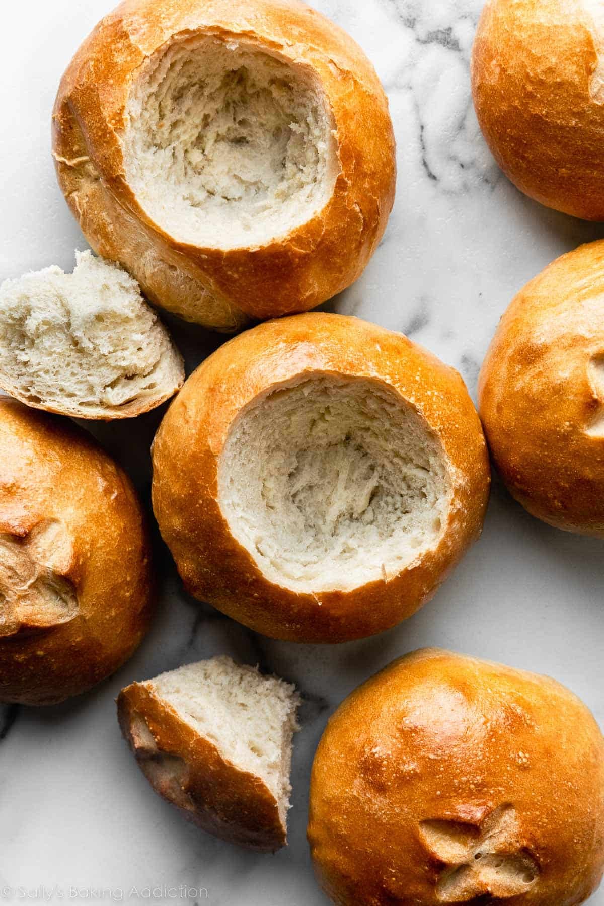 bread bowls on marble counter with center pulled out of some.