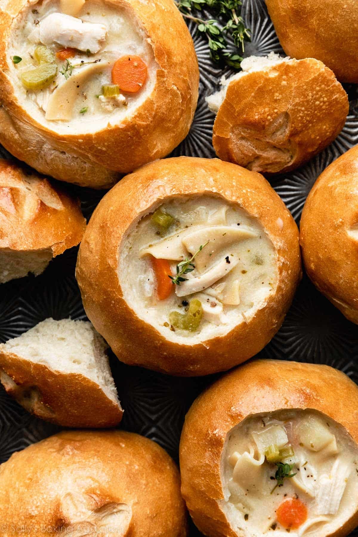 bread bowls on baking sheet filled with chicken noodle soup.