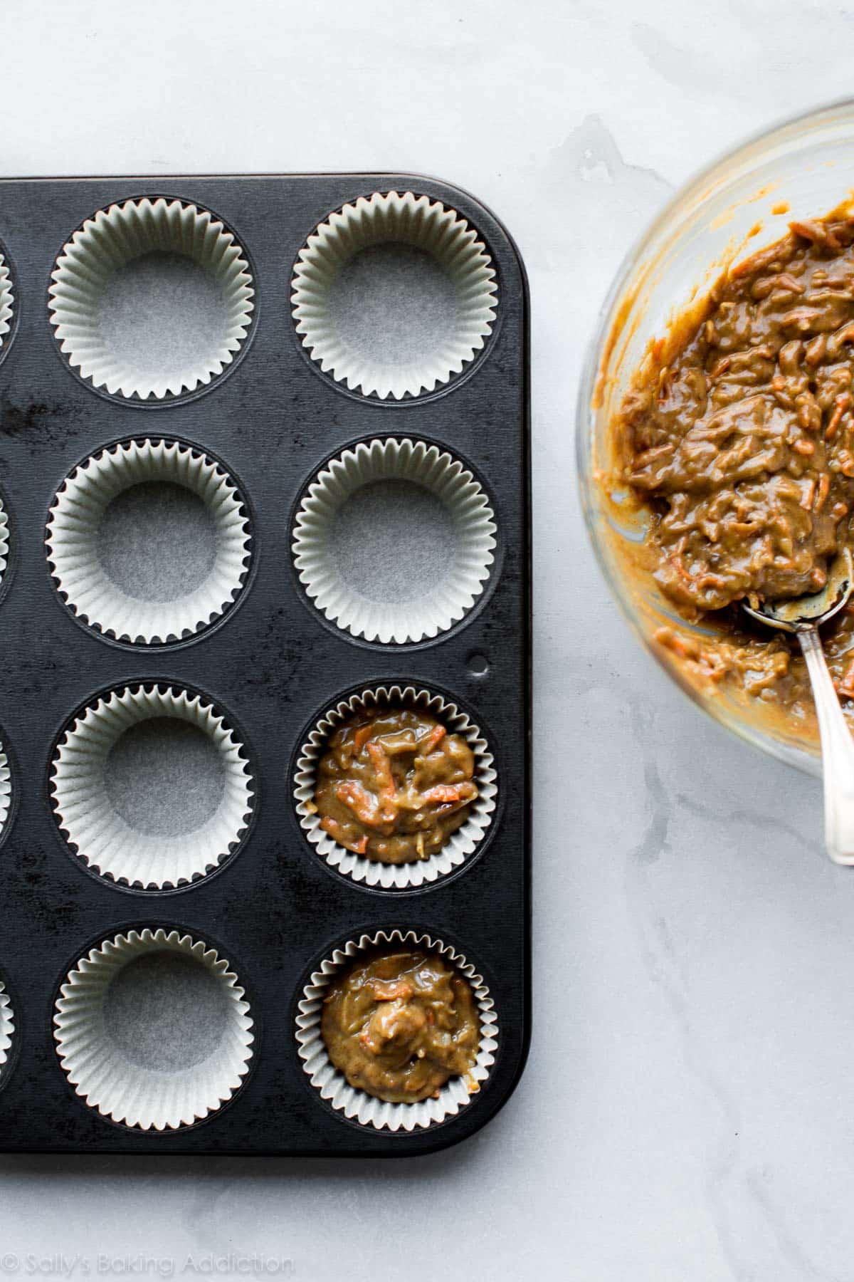 carrot cake cupcake batter in a glass bowl and cupcake batter in a cupcake pan