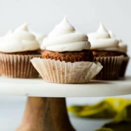 carrot cake cupcakes on a marble and wood cake stand