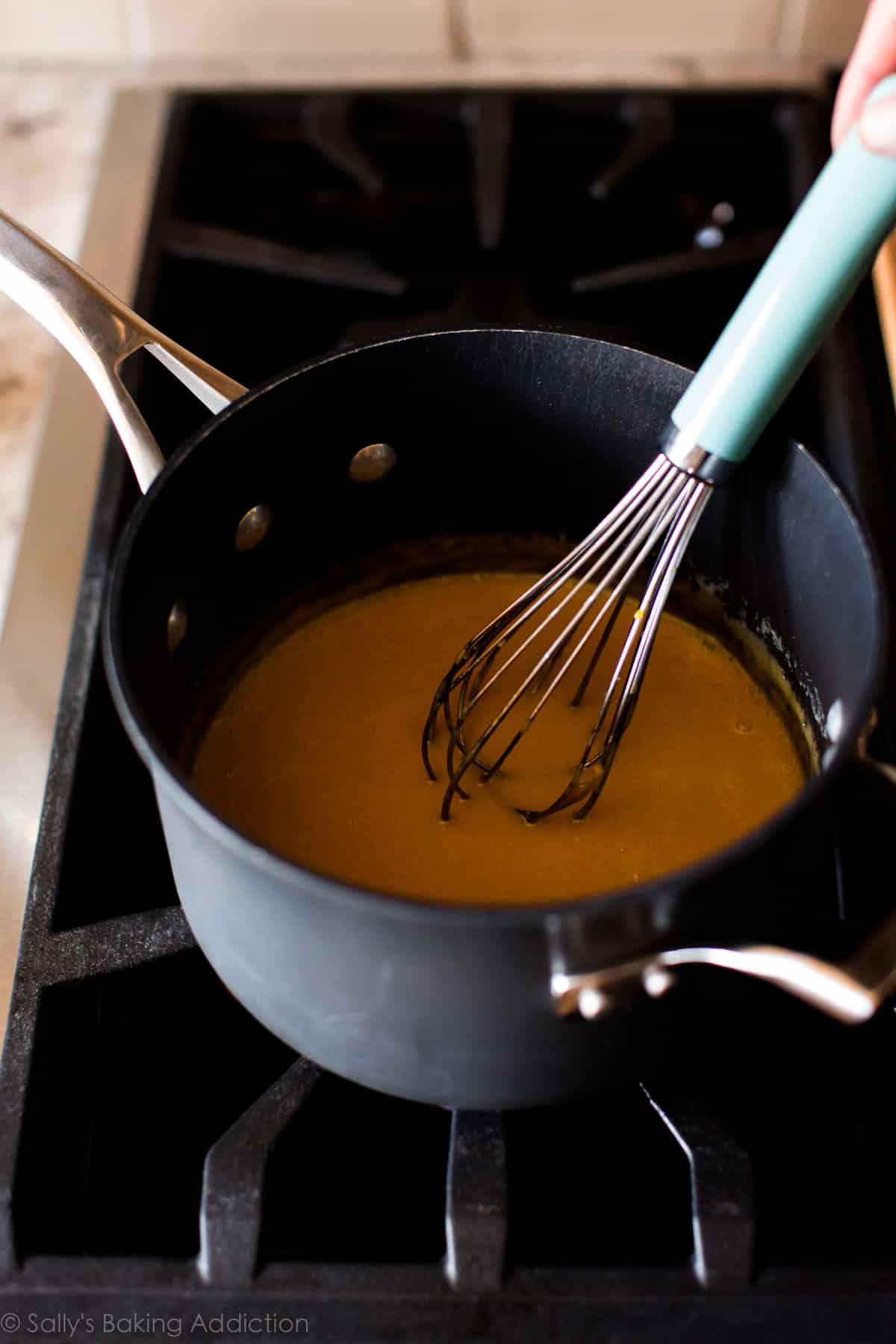 wet ingredients for coconut pecan filling in a saucepan on the stove with a whisk