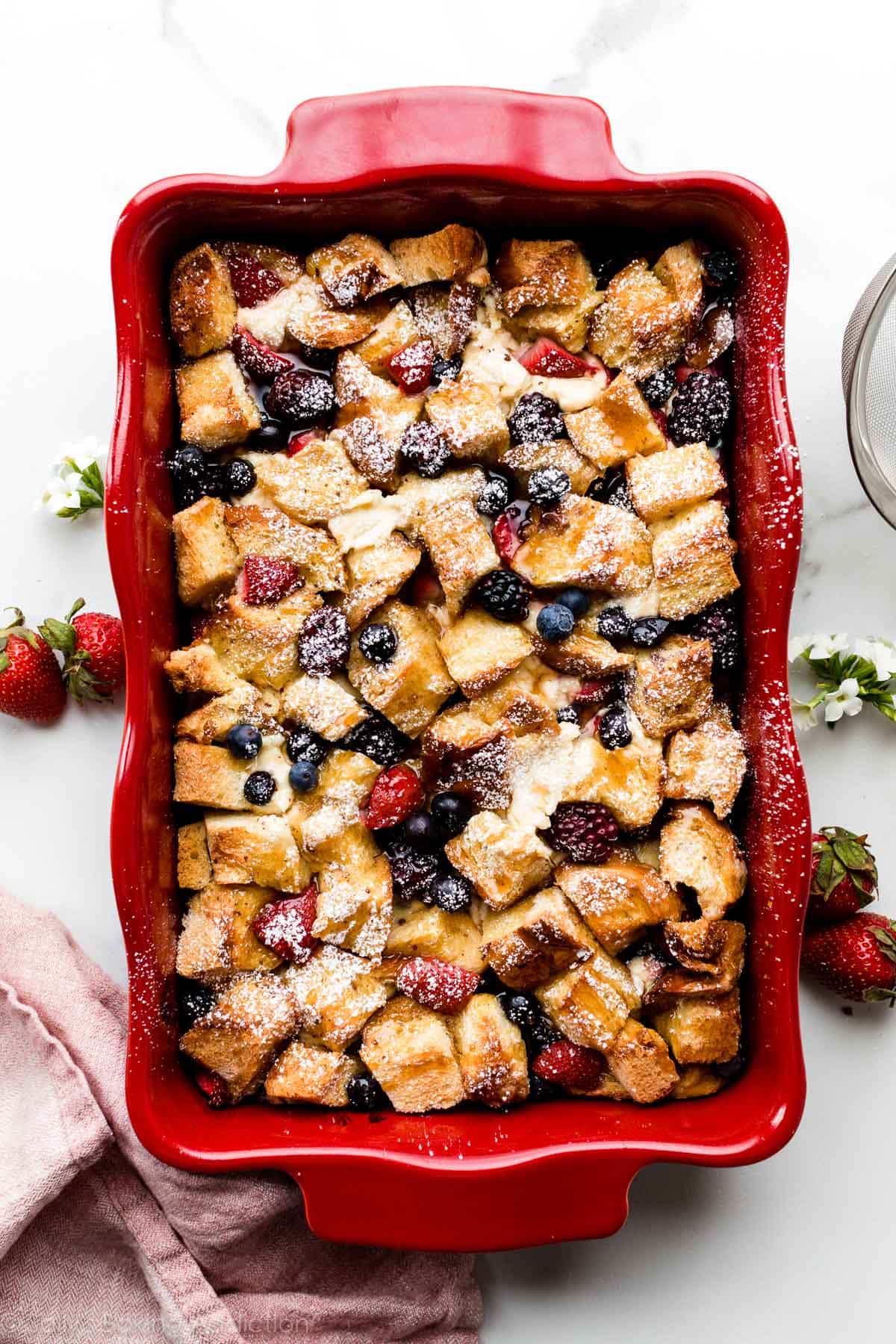 French toast casserole bake with cream cheese, blueberries, blackberries, and strawberries in red casserole dish