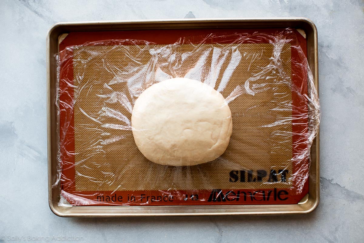 croissant dough in a ball on a baking sheet covered with plastic wrap