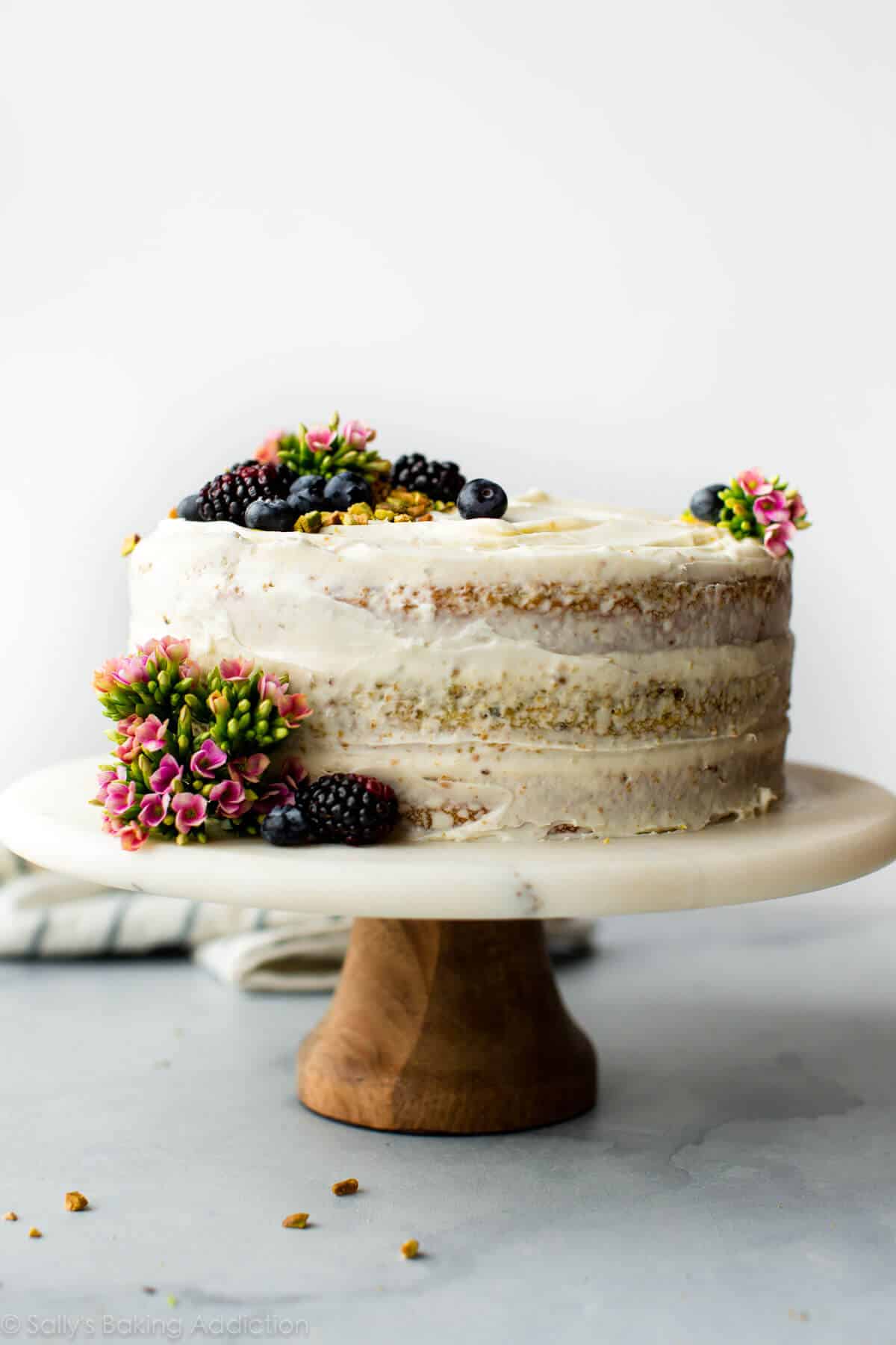 pistachio cake on a wood and marble cake stand