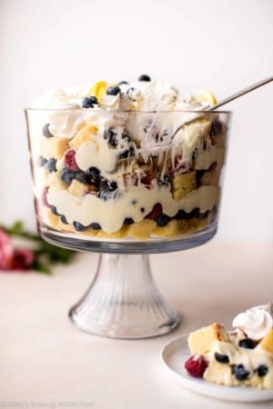 lemon berry trifle with a serving spoon and a serving of trifle on a white plate