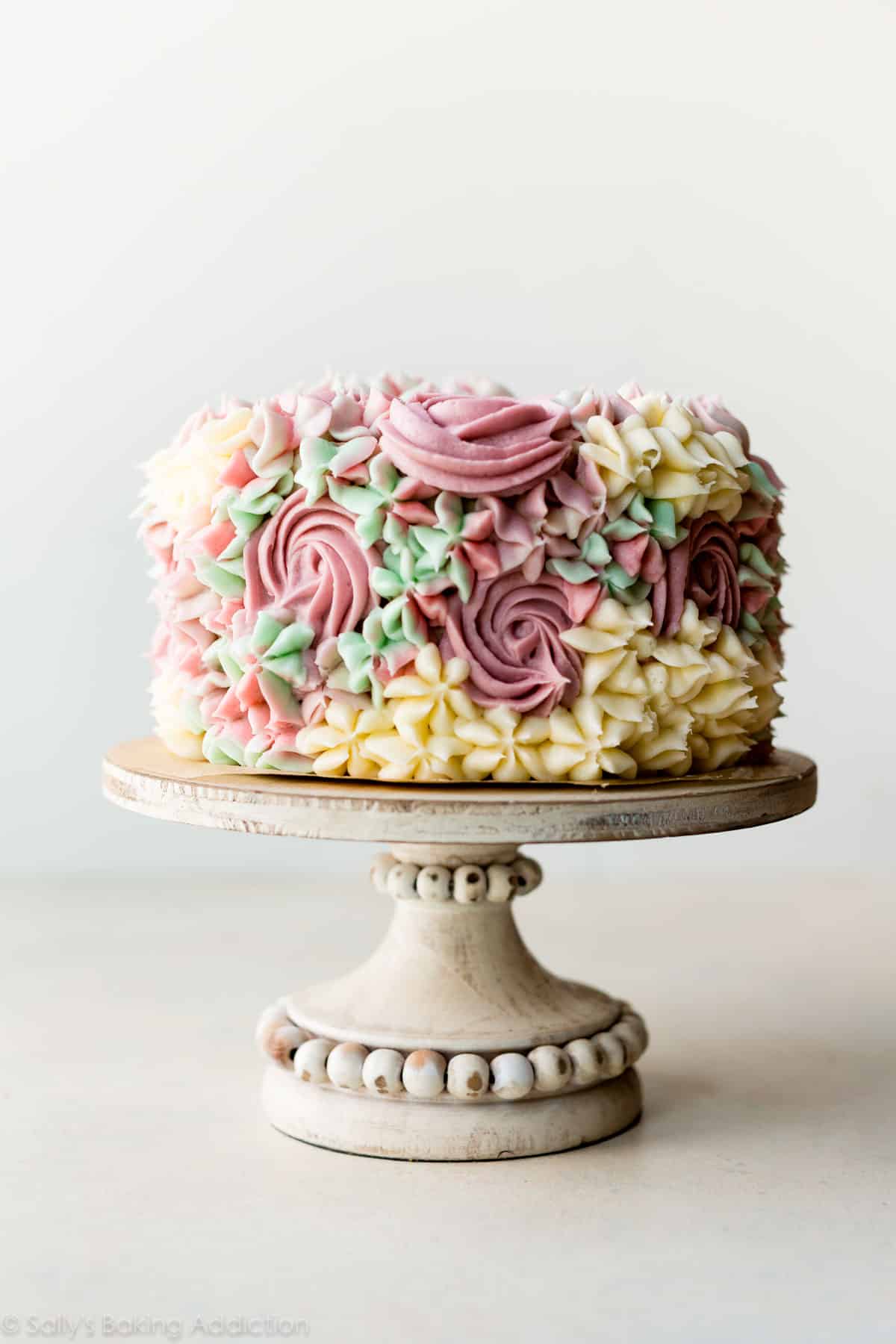 6 inch cake with floral piping decoration on a cake stand