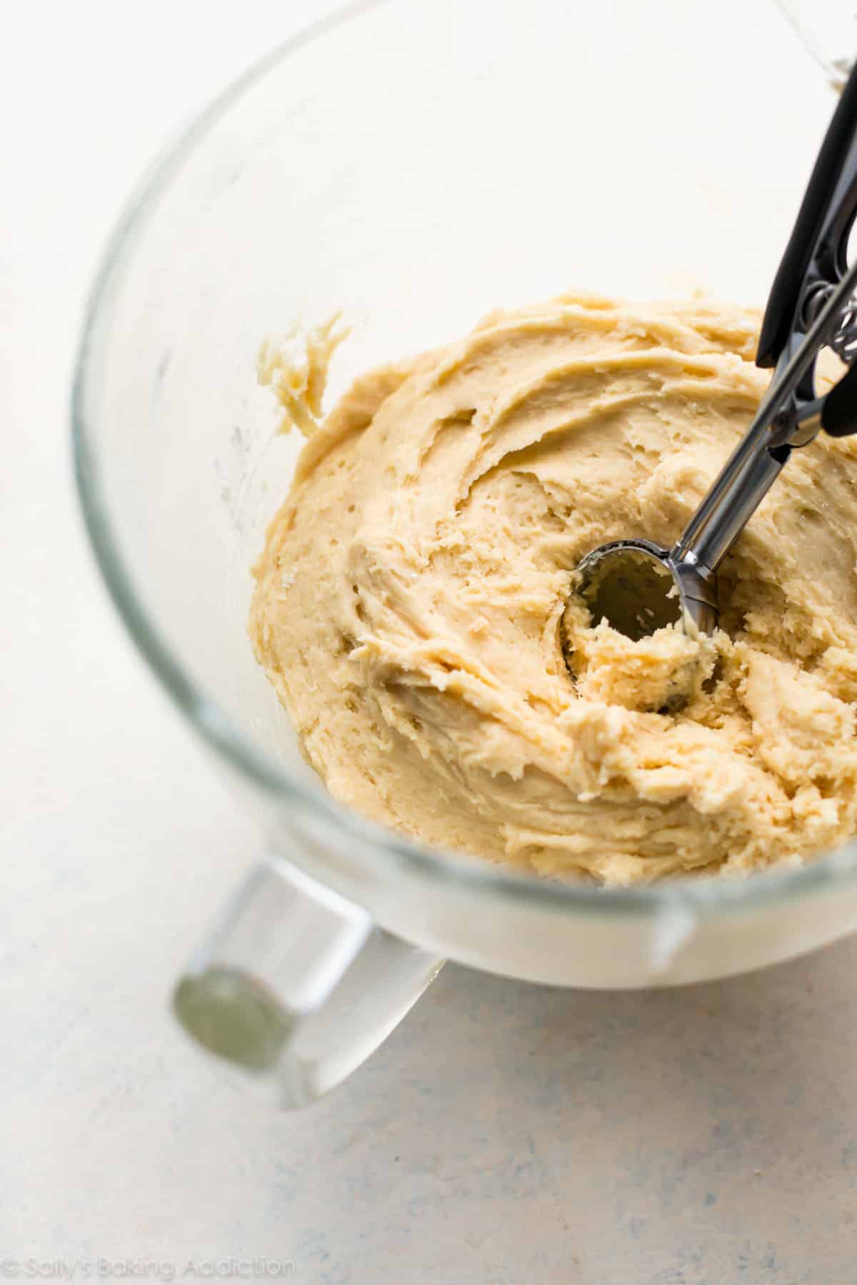 cookie dough in a glass bowl with a cookie scoop