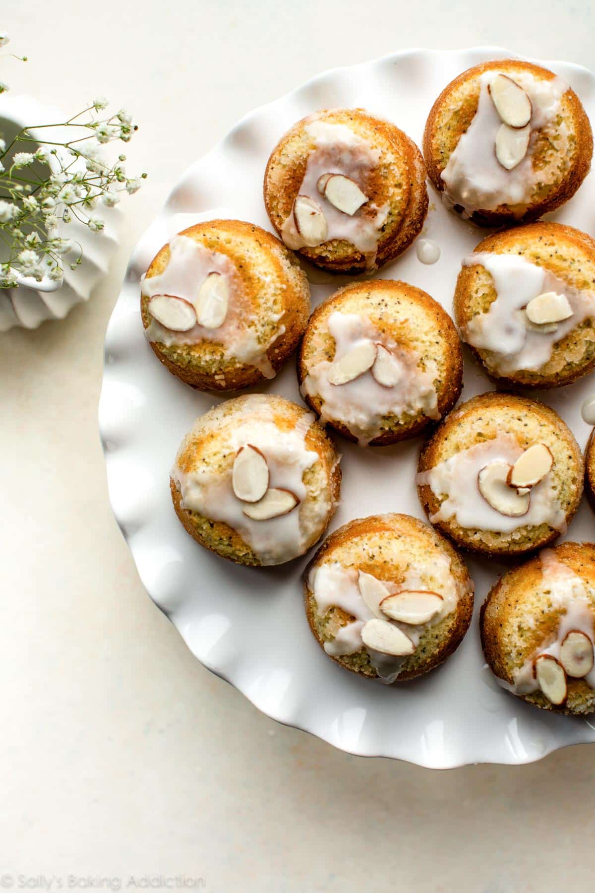 overhead image of almond poppy seed tea cakes on a white cake stand