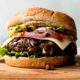 black bean burger with a bun, onions, cheese, lettuce, and avocado