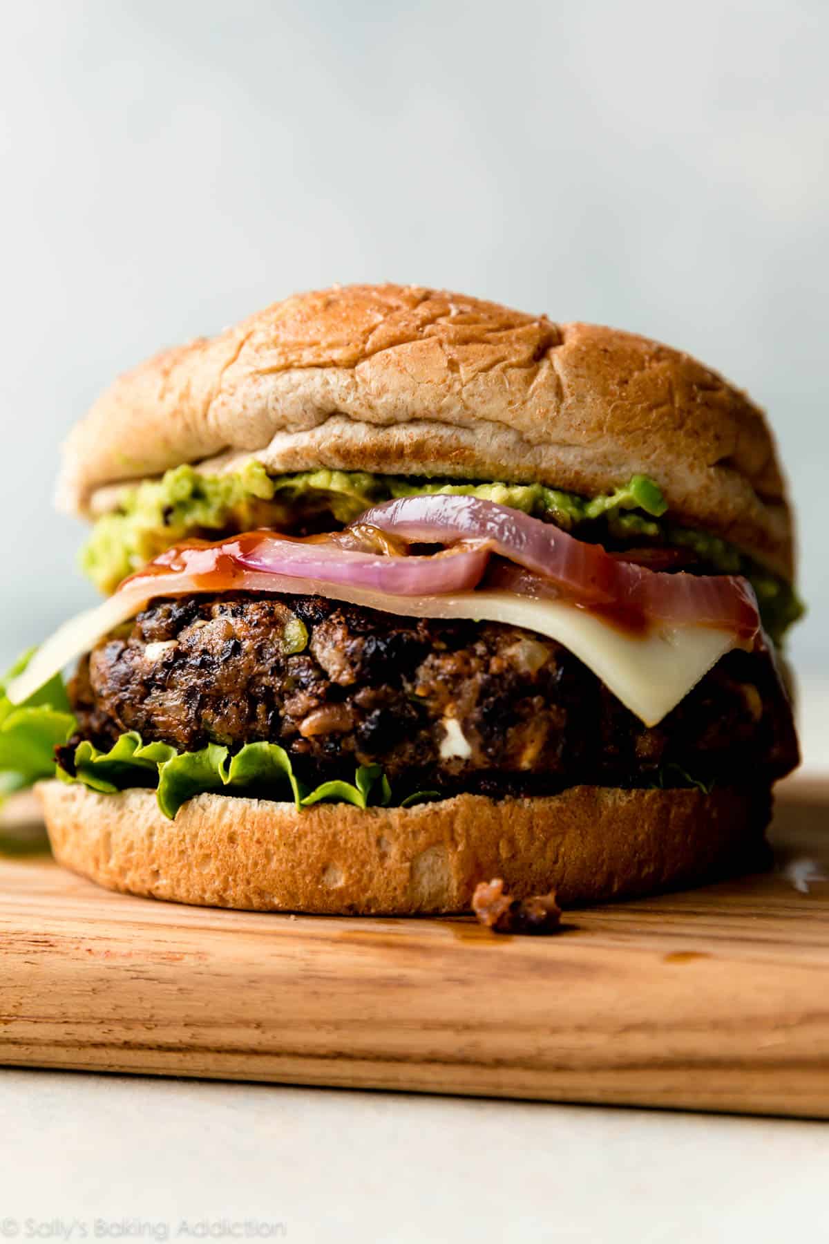 black bean burger with a bun, onions, cheese, lettuce, and avocado