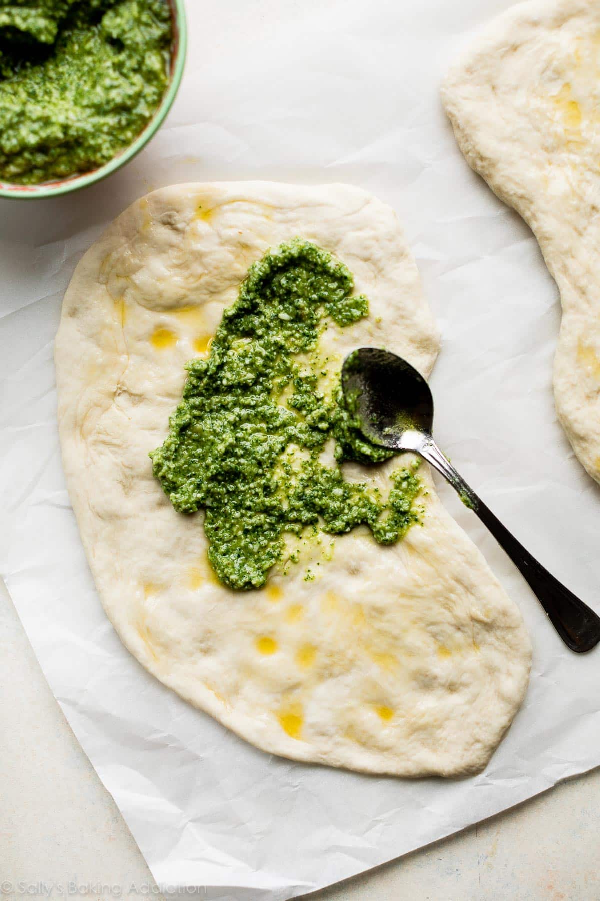 spreading pesto on flatbread dough