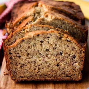 homemade banana bread slices on wooden cutting board.