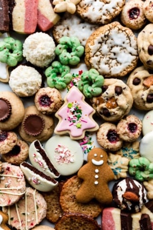 assortment of Christmas cookies including sugar cookies, gingerbread cookies, thumbprints, oatmeal cookies, coconut macaroons, and spritz cookies