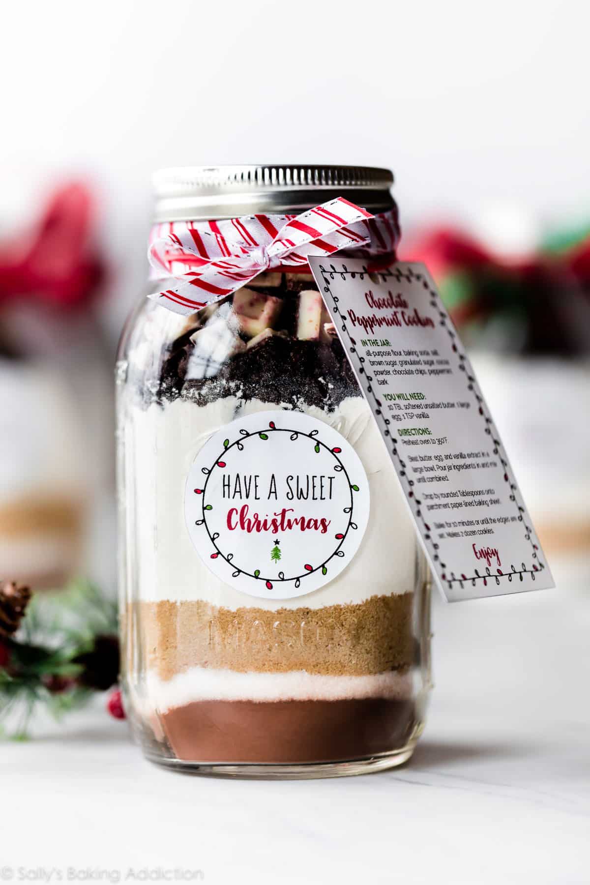 glass jar with ingredients for cookies decorated with ribbon and a recipe card