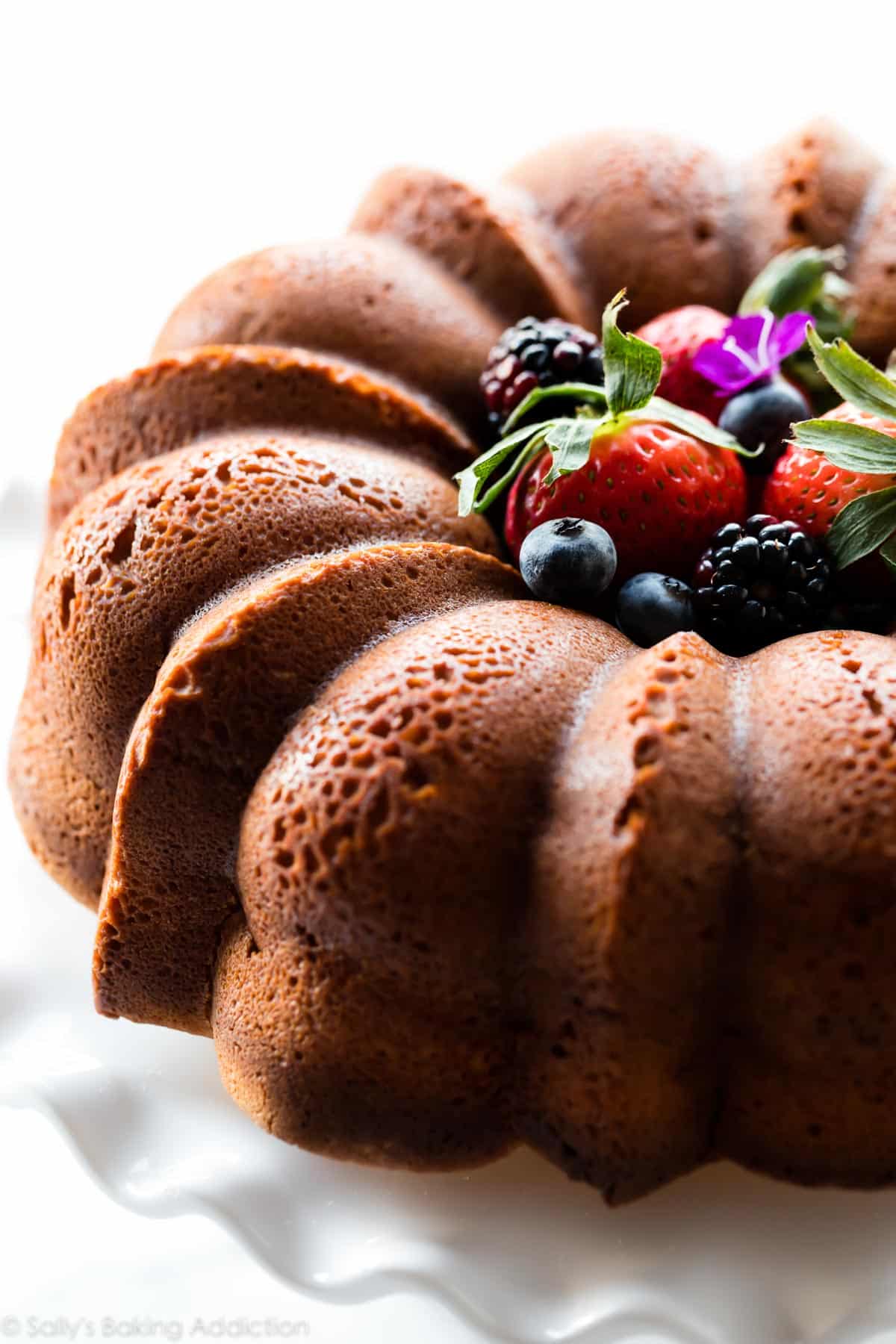 Cream cheese pound cake on a white cake stand with berries in the center