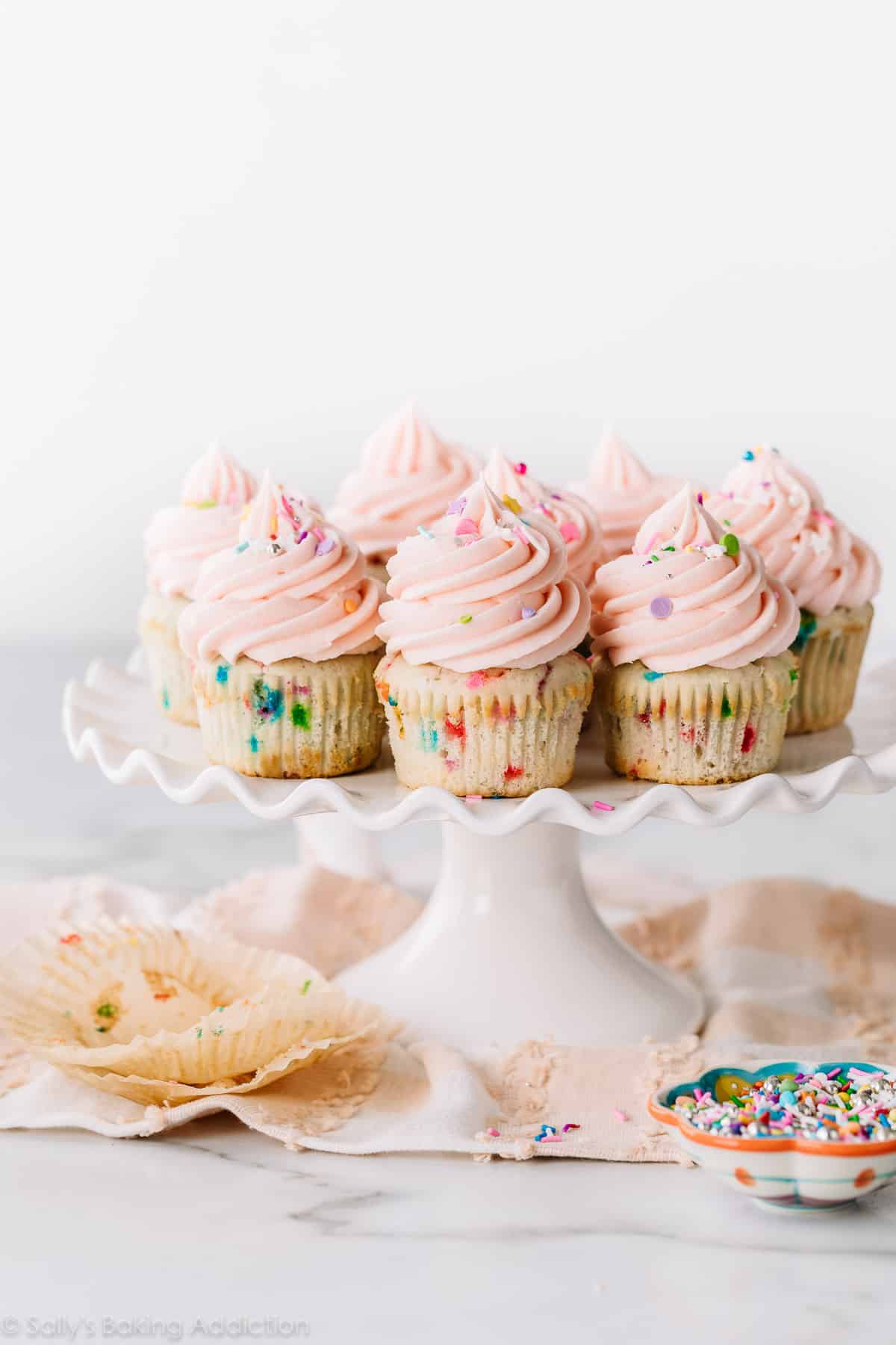 Vanilla cupcakes with pink frosting on white cake stand