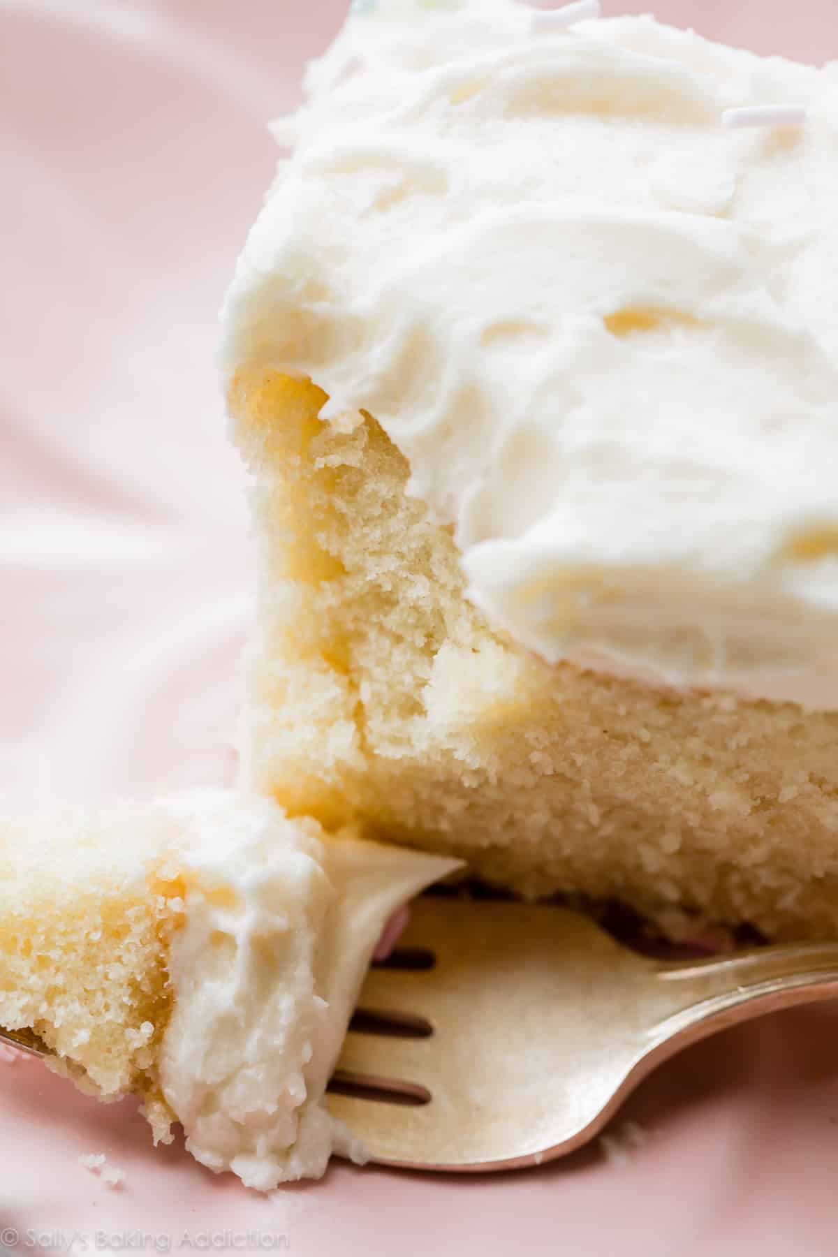 slice of vanilla sheet cake on a pink plate with a fork