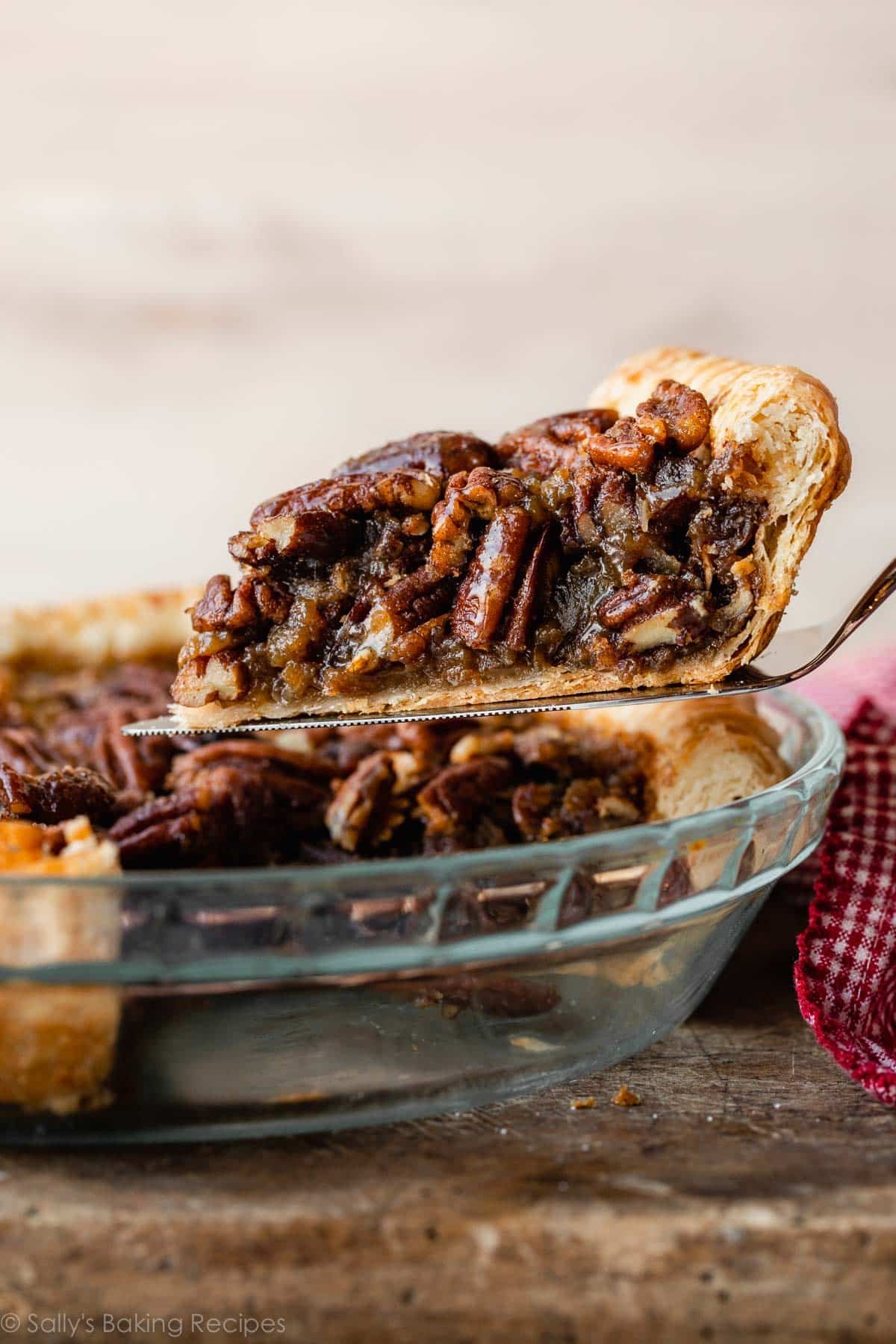 pie server holding pecan pie slice over pie dish.