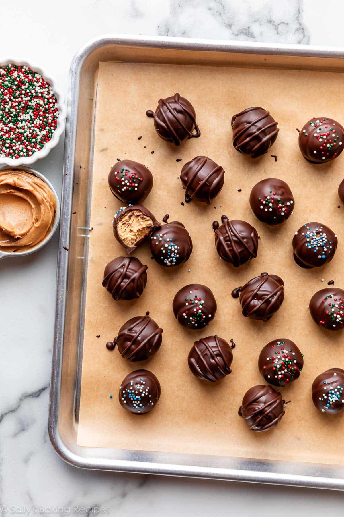 coated peanut butter balls on lined baking sheet.