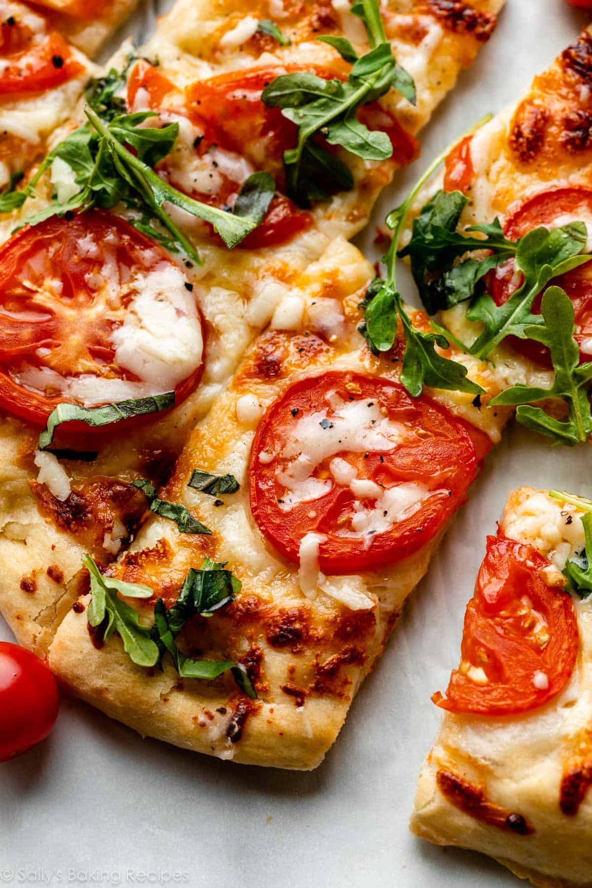 homemade flatbread pizza with mozzarella cheese, tomatoes, and arugula on top.