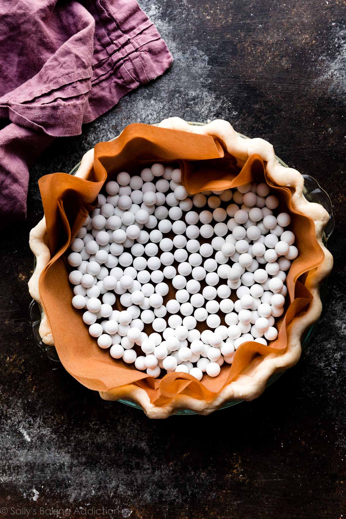 white pie weights in a pie crust shell