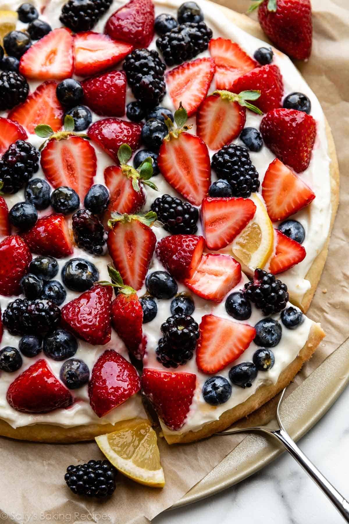 lemon berry dessert fruit pizza with strawberries, blackberries, blueberries, and a lemon slices on top.