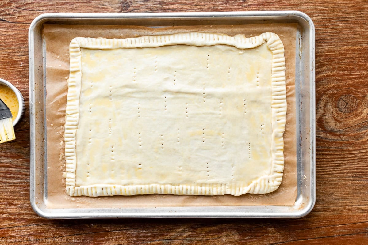 pastry dough rolled out on baking sheet with egg wash