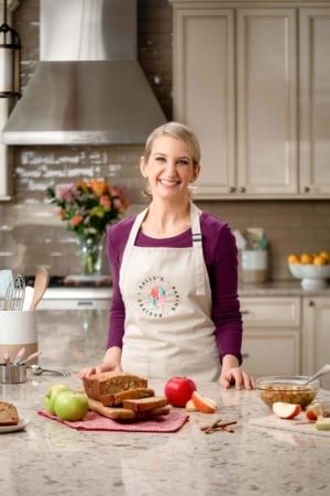 Sally at counter with apples, bread, and other baking ingredients.